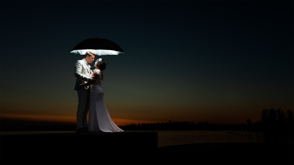 Bruidsfoto van een stralend bruidspaar dat elkaar liefdevol aankijkt, met een prachtige achtergrond vol natuurlijke kleuren die de romantische sfeer van de trouwdag benadrukt.